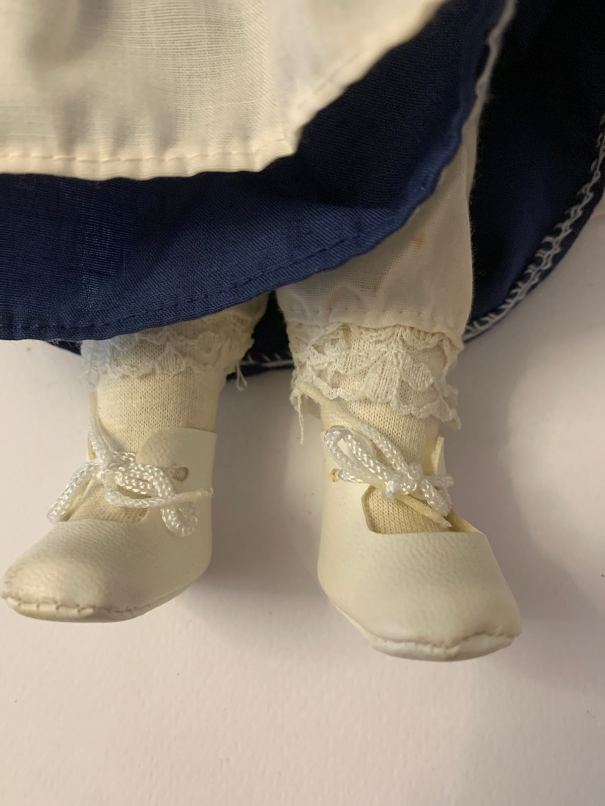 Bambola di porcellana vintage con trecce, occhiali e vestito blu con grembiule