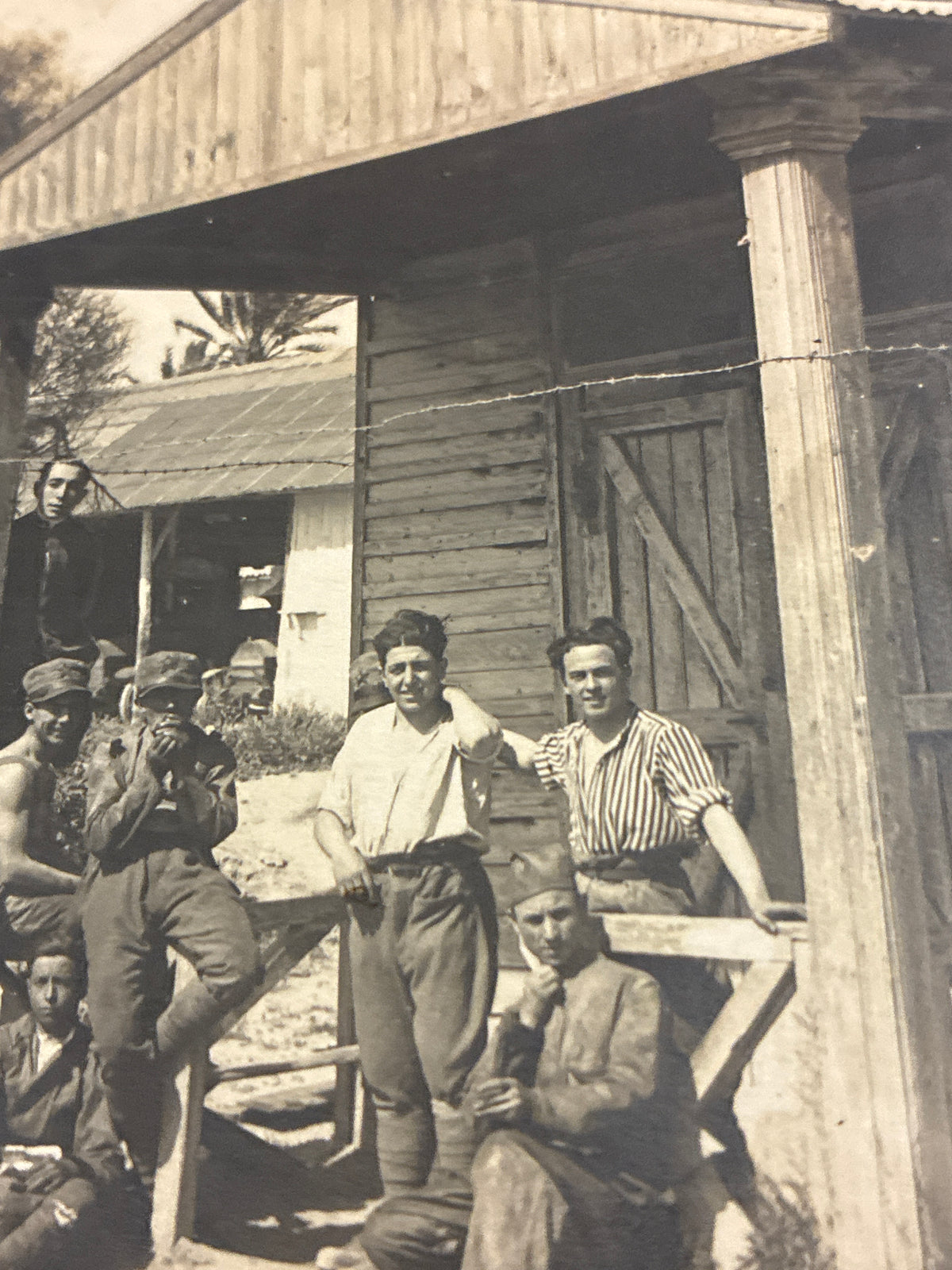 Cartolina postale italiana d'epoca coloniale con soldati e ufficiali del Regio Esercito in posa davanti a un baraccamento militare in legno.