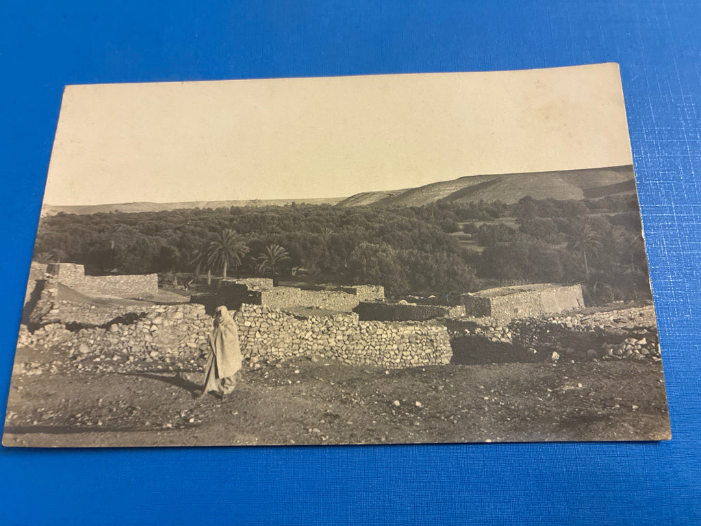 Cartolina postale italiana d'epoca coloniale del 1919 con veduta di Beni Ulid in Libia e indigeno locale in abiti tradizionali arabi.