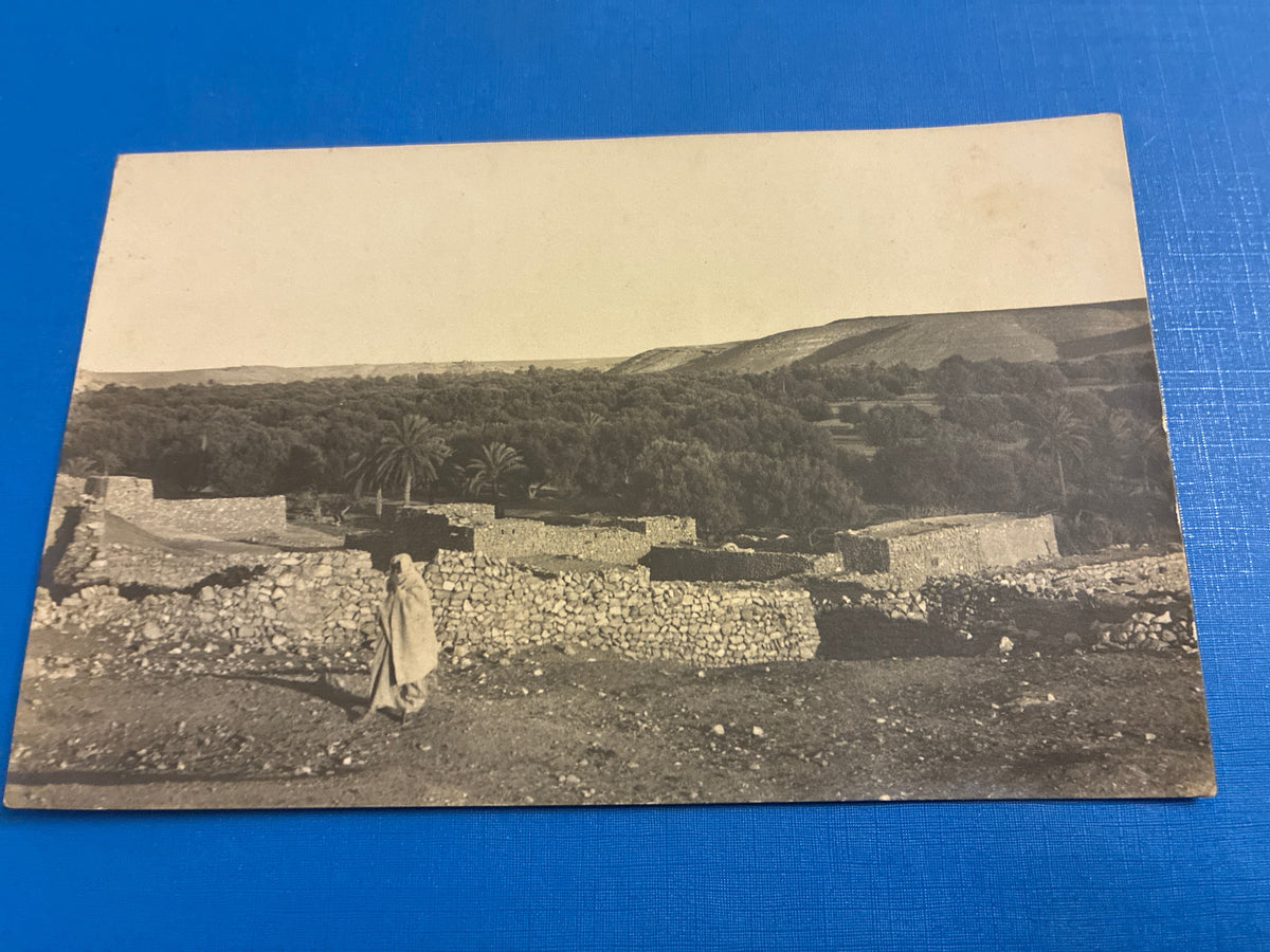 Cartolina postale italiana d'epoca coloniale del 1919 con veduta di Beni Ulid in Libia e indigeno locale in abiti tradizionali arabi.