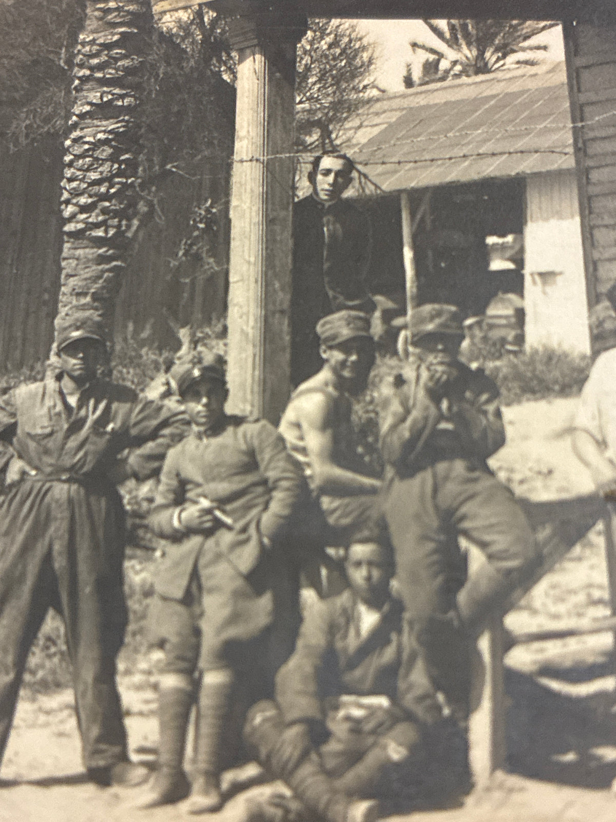 Cartolina postale italiana d'epoca coloniale con soldati e ufficiali del Regio Esercito in posa davanti a un baraccamento militare in legno.